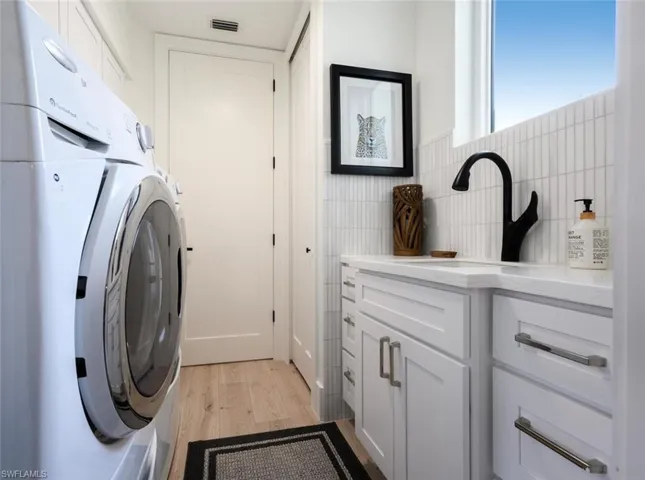 Renovated laundry room w/quartz counter tops, tub sink, custom cabinets, panty/closet and front load washer & dryer