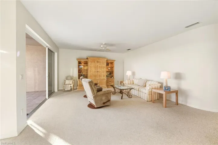 Carpeted living area featuring ceiling fan and baseboards