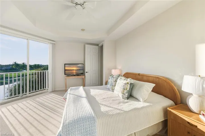 Bedroom with a tray ceiling, carpet flooring, ceiling fan, and access to outside
