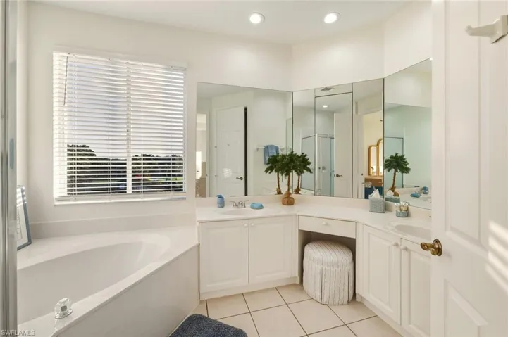 Full bathroom featuring double vanity, a garden tub, light tile patterned floors, a shower stall, and recessed lighting