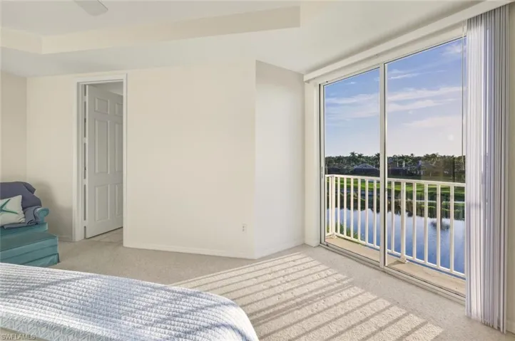 Bedroom with a water view, access to outside, light carpet, and ceiling fan