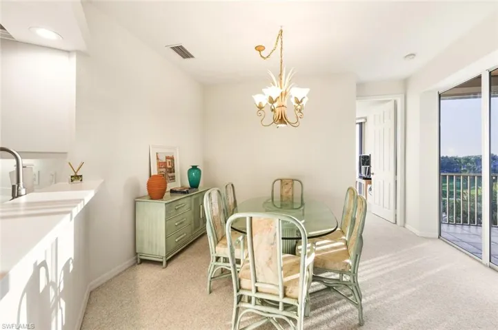Dining space with light carpet and a chandelier