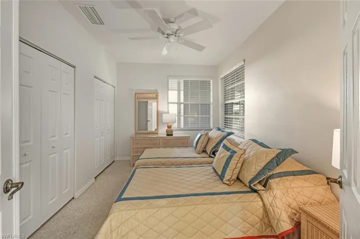 Bedroom with multiple closets, light carpet, and ceiling fan