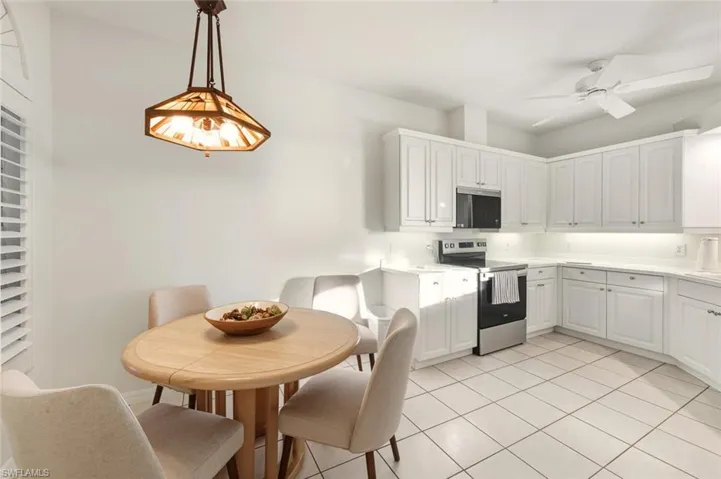 Kitchen with stainless steel appliances, light countertops, white cabinets, and a ceiling fan