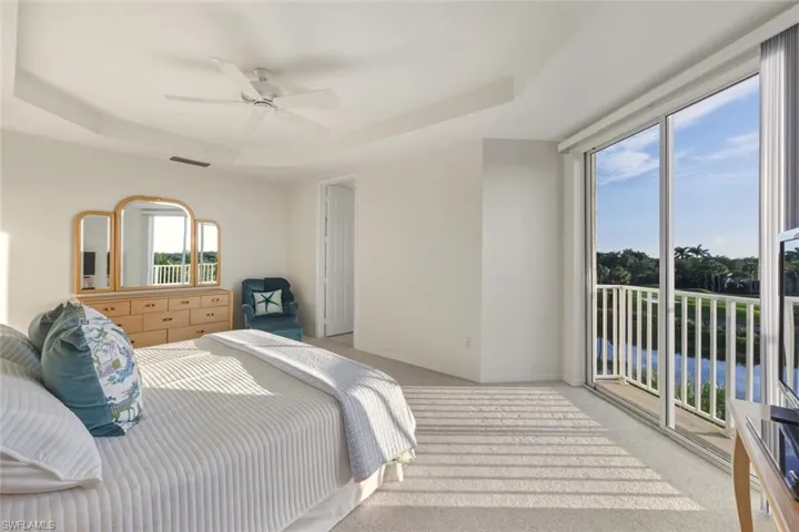 Bedroom with a raised ceiling, access to outside, light colored carpet, and ceiling fan