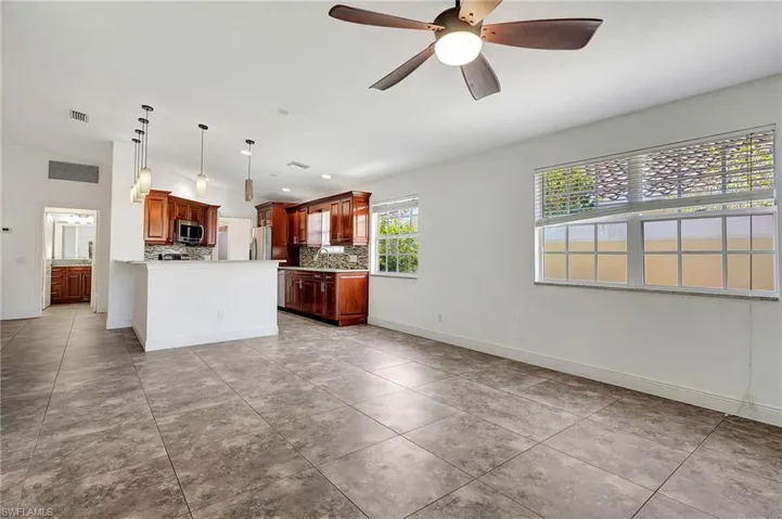 Kitchen with decorative light fixtures, a ceiling fan, decorative backsplash, stainless steel appliances, and light tile patterned flooring