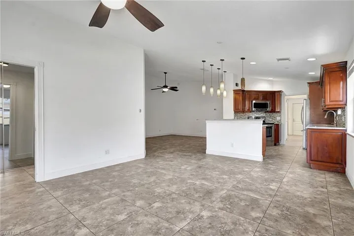 Kitchen featuring pendant lighting, open floor plan, a ceiling fan, and stainless steel appliances