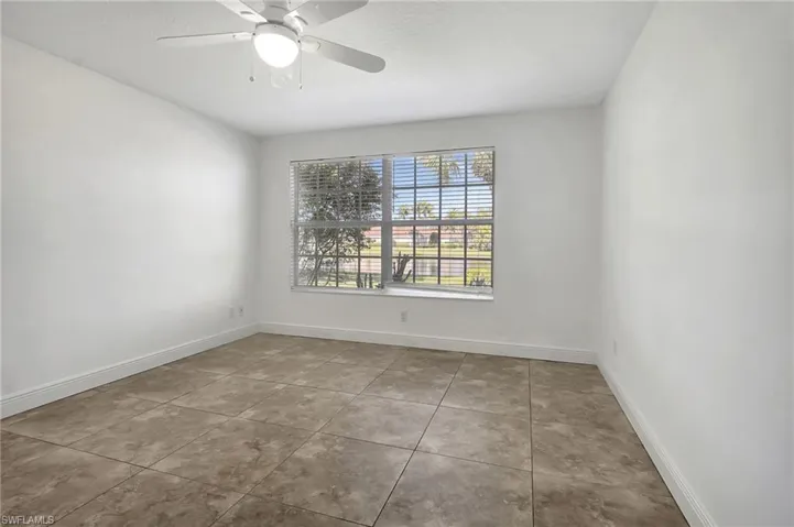 Master bedroom featuring a ceiling fan and light tile patterned floors.