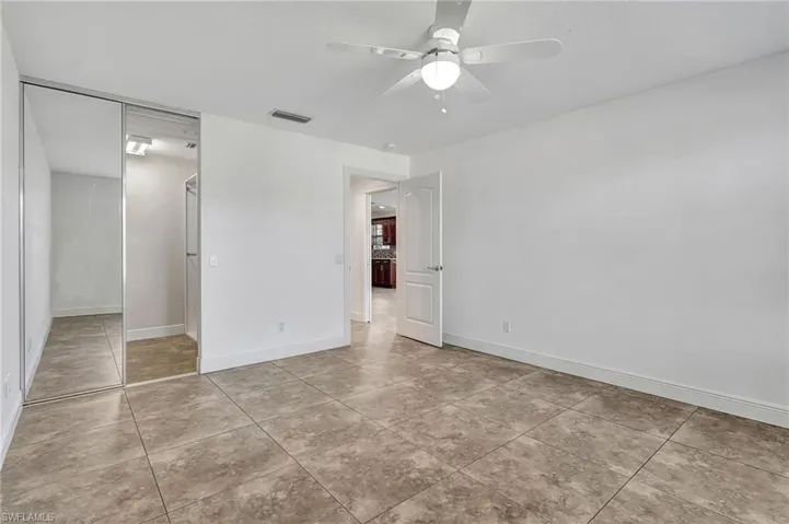 Master bedroom featuring a ceiling fan and light tile patterned floors.