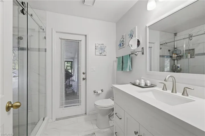 Bathroom featuring vanity, light marble finish flooring, and a shower.  Bonus a door to the pool!