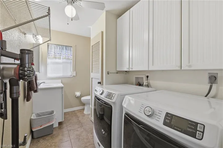 Laundry room with washing machine and clothes dryer, storage cabinets, and 1/2 Bathroom.