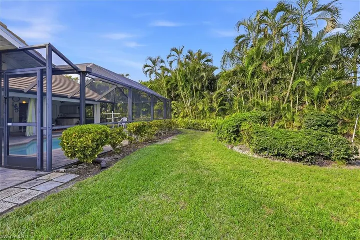 View of lush green lawn featuring a screened lanai, outdoor pool, and a patio
