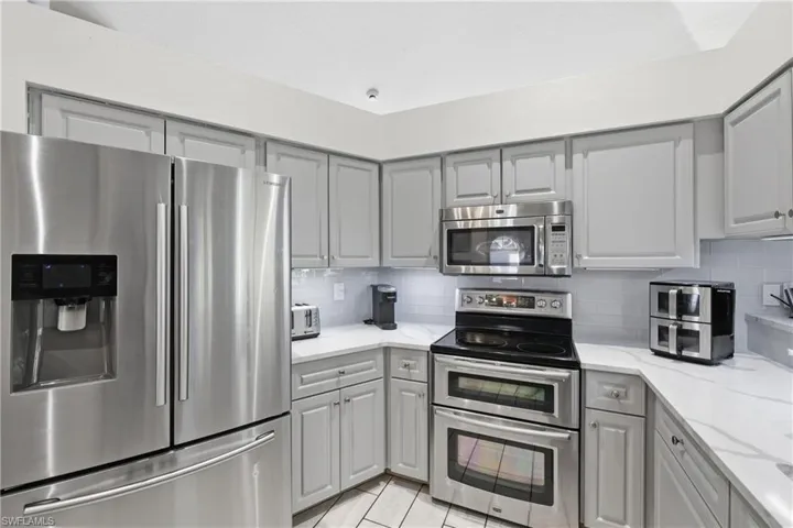Kitchen featuring light gray cabinets, appliances with stainless steel finishes, and wonderful backsplash