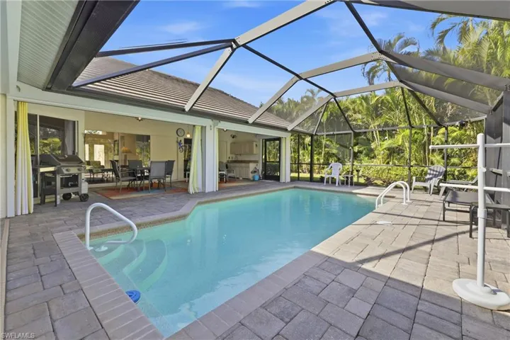 Relax in the beautiful private pool featuring a screened lanai, heated pool, covered seating, a grill, and outdoor dining area