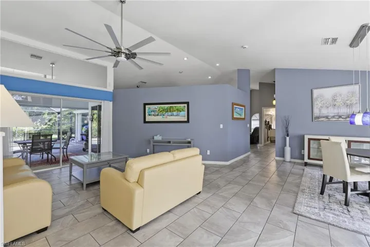 Living room featuring vaulted ceiling, ceiling fan, and light tile floors