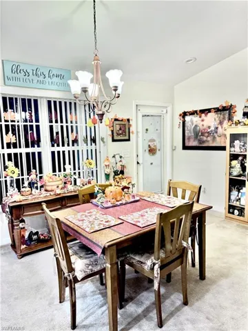 Dining area with light colored carpet, a chandelier, and recessed lighting