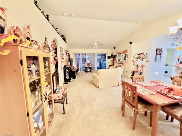 Dining area featuring arched walkways, light carpet, lofted ceiling, a ceiling fan, and a chandelier