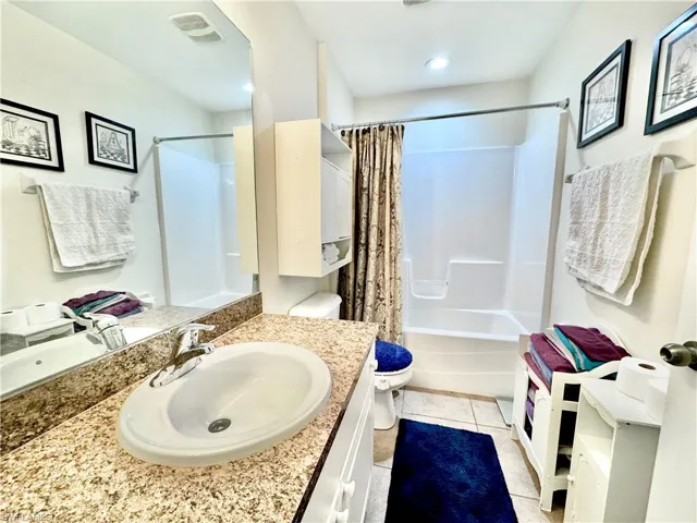 Full bathroom featuring light tile patterned floors, shower / bathtub combination with curtain, and vanity