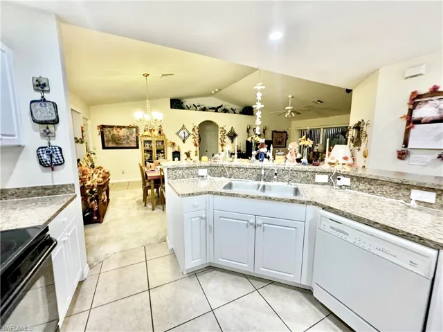 Kitchen featuring black electric range oven, dishwasher, vaulted ceiling, white cabinetry, and a chandelier