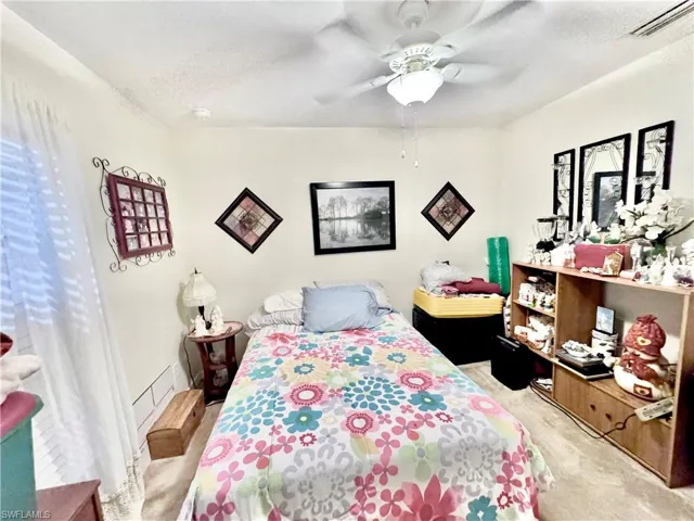 Bedroom with light colored carpet, a textured ceiling, and ceiling fan