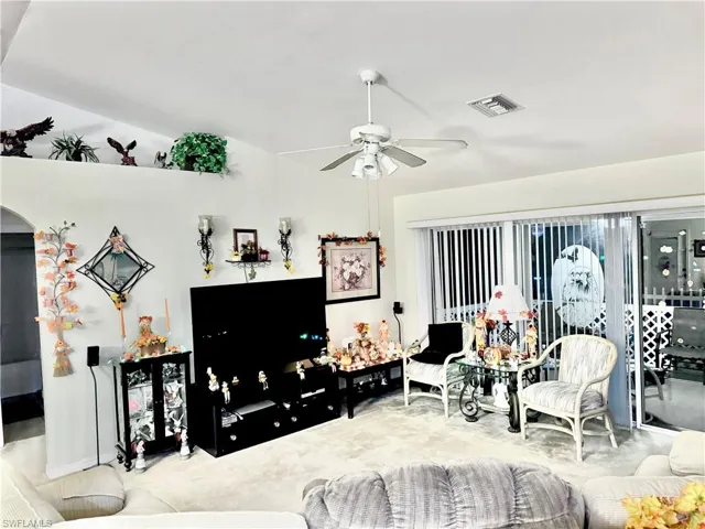 Living room featuring carpet flooring, ceiling fan, and arched walkways