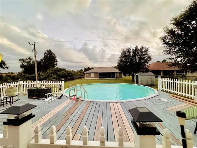 View of swimming pool with a fenced backyard, a wooden deck, and a shed