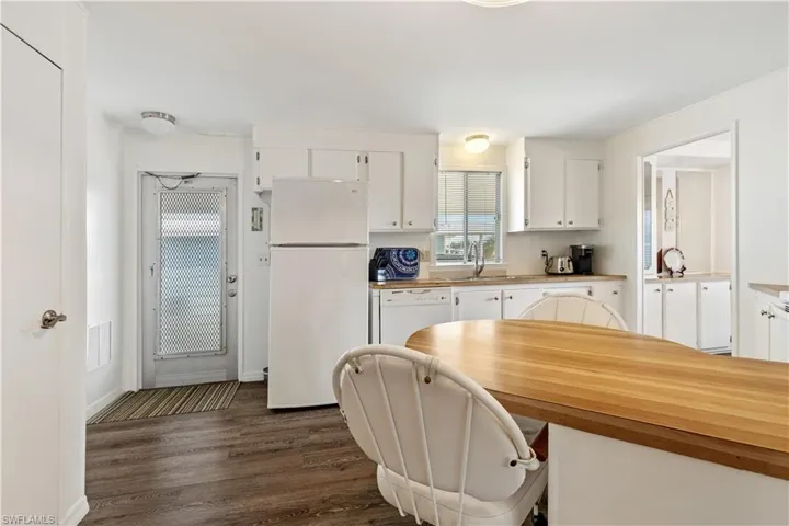 Kitchen featuring freestanding refrigerator, white cabinetry, dark wood finished floors, and butcher block counters