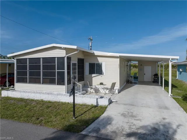 Manufactured / mobile home featuring a front yard, a carport, concrete driveway, and a sunroom