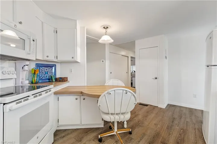 Kitchen with white appliances, light white cabinets, and decorative light fixtures