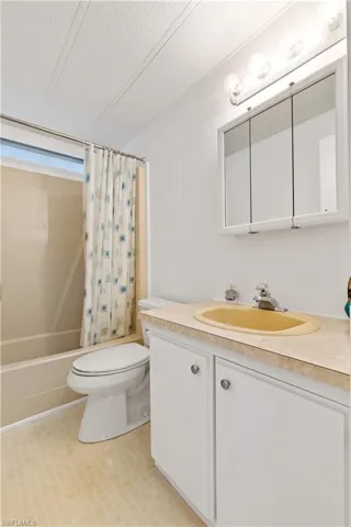 Bathroom featuring vanity, shower / bath combo, and a textured ceiling