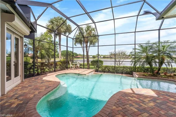 Outdoor pool with a sunroom, a patio, glass enclosure, and a water view