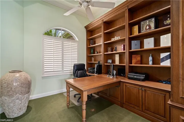 Home office featuring crown molding, dark colored carpet, and ceiling fan