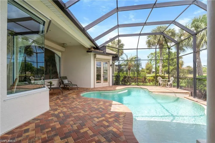 Swimming pool with a sunroom, glass enclosure, a patio area, and french doors