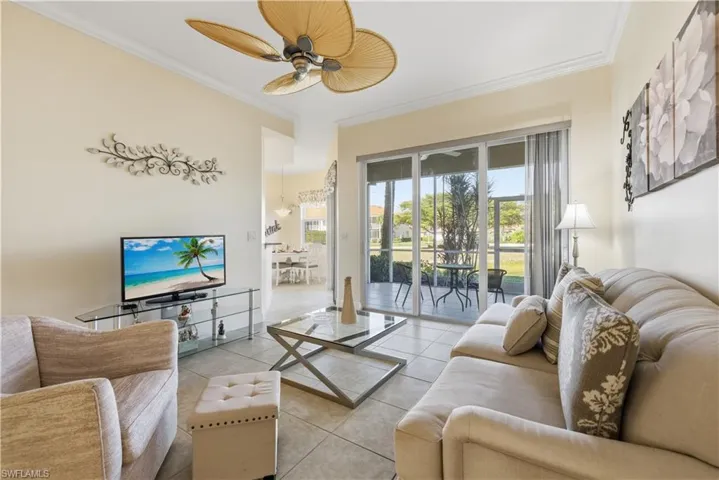 Living room featuring ornamental molding, tile patterned floors, and ceiling fan