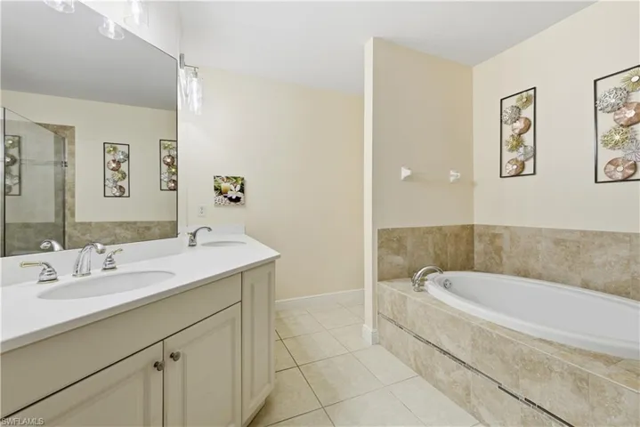 Full bathroom with double vanity, a garden tub, light tile patterned flooring, and a tile shower