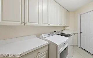 Laundry area with cabinet space, light tile patterned floors, and washer and dryer