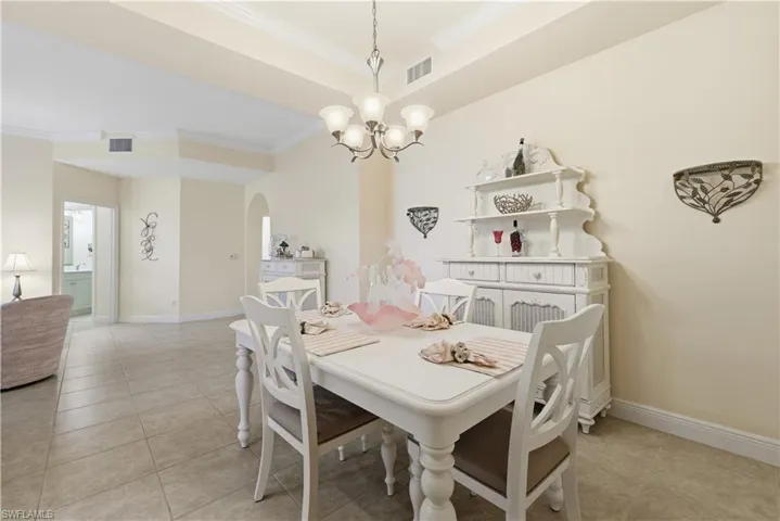 Dining area featuring a chandelier, ornamental molding, arched walkways, and light tile patterned floors