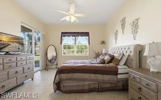 Bedroom featuring access to exterior, light tile patterned flooring, and ceiling fan