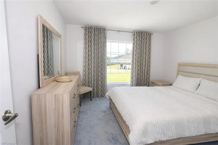 This room features light gray carpeting, a window with curtains, and a ceiling light fixture