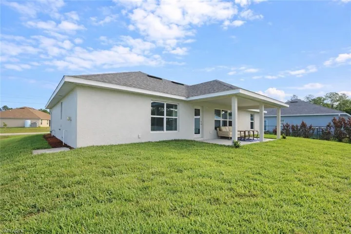 The property features a stucco exterior, a covered patio, and a spacious green lawn