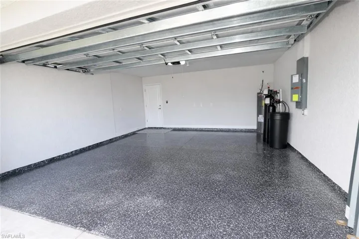 The garage features a speckled epoxy floor, white textured walls, and an overhead garage door mechanism