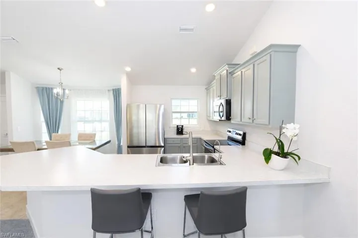 The kitchen features light-toned countertops, a double basin sink, and stainless steel appliances