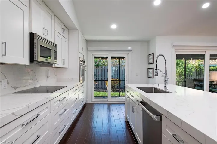 Kitchen featuring light stone countertops, recessed lighting, white cabinetry, dark wood-style floors, and stainless steel appliances