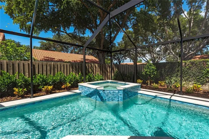 View of pool featuring glass enclosure, a sunroom, a pool with connected hot tub, and a fenced backyard