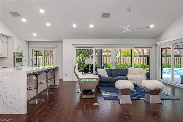 Living area with vaulted ceiling, recessed lighting, dark wood-type flooring, and ceiling fan