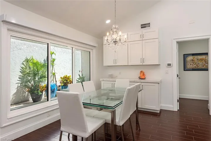 Dining space with wood tiled floors, vaulted ceiling, a chandelier, and recessed lighting