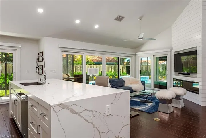 Kitchen featuring recessed lighting, wood finish floors, white cabinets, plenty of natural light, and light stone counters
