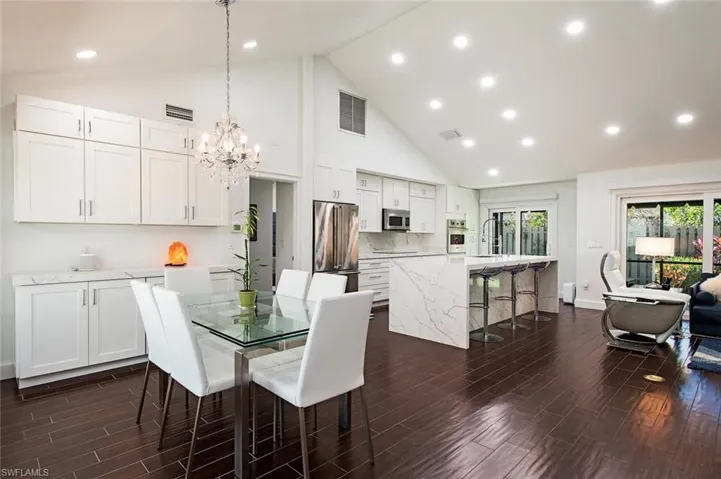 Dining room featuring wood tiled floors, high vaulted ceiling, recessed lighting, and a chandelier