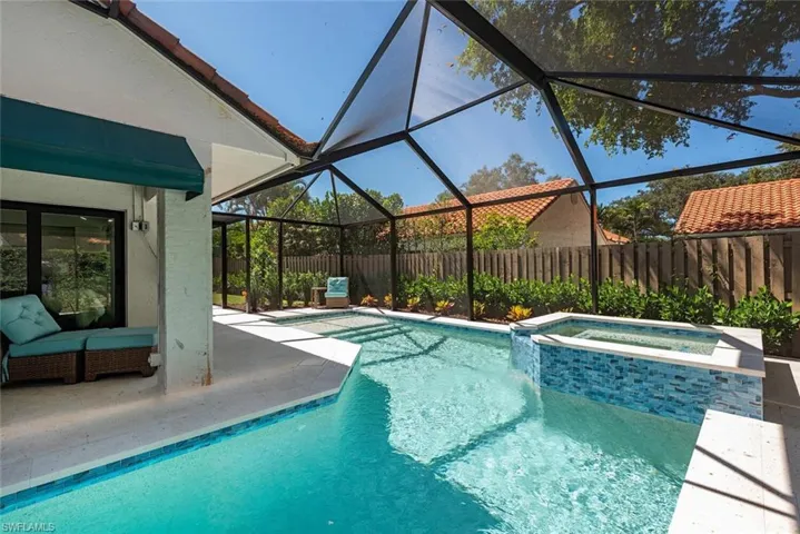 View of swimming pool with glass enclosure, a sunroom, a patio, a pool with connected hot tub, and a fenced backyard