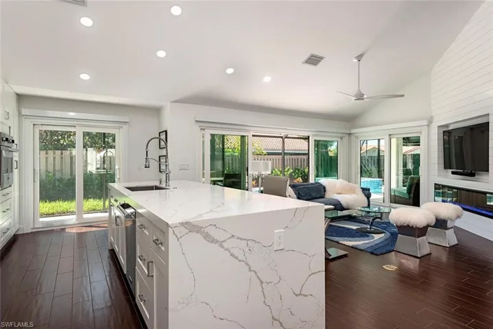 Kitchen featuring white cabinetry, light stone counters, recessed lighting, open floor plan, and dark wood-style flooring